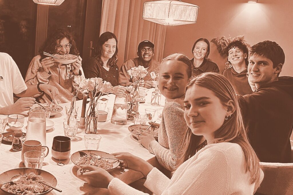Jongeren eten samen aan een lange tafel